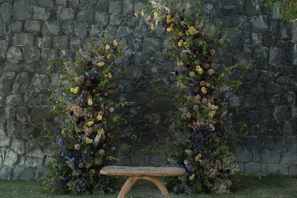 Romantic garden-style wedding flowers featuring mauve, blush, plum, and buttery yellow blooms styled by a wedding florist in San Miguel de Allende, Mexico. The bouquet and floral centerpiece include lisianthus, ranunculus, and delicate filler flowers, perfect for an elegant destination wedding. Captured at Casa Adela with soft candlelight and seasonal fruits, the floral design blends old-world charm with modern romance.