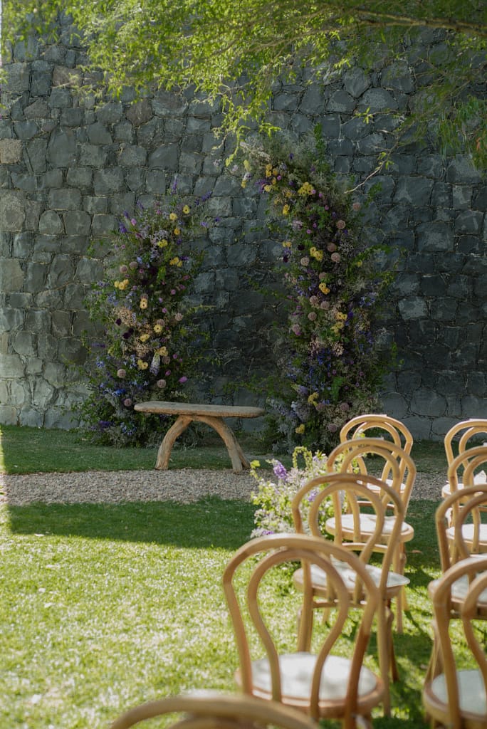 Romantic garden-style wedding flowers featuring mauve, blush, plum, and buttery yellow blooms styled by a wedding florist in San Miguel de Allende, Mexico. The bouquet and floral centerpiece include lisianthus, ranunculus, and delicate filler flowers, perfect for an elegant destination wedding. Captured at Casa Adela with soft candlelight and seasonal fruits, the floral design blends old-world charm with modern romance.