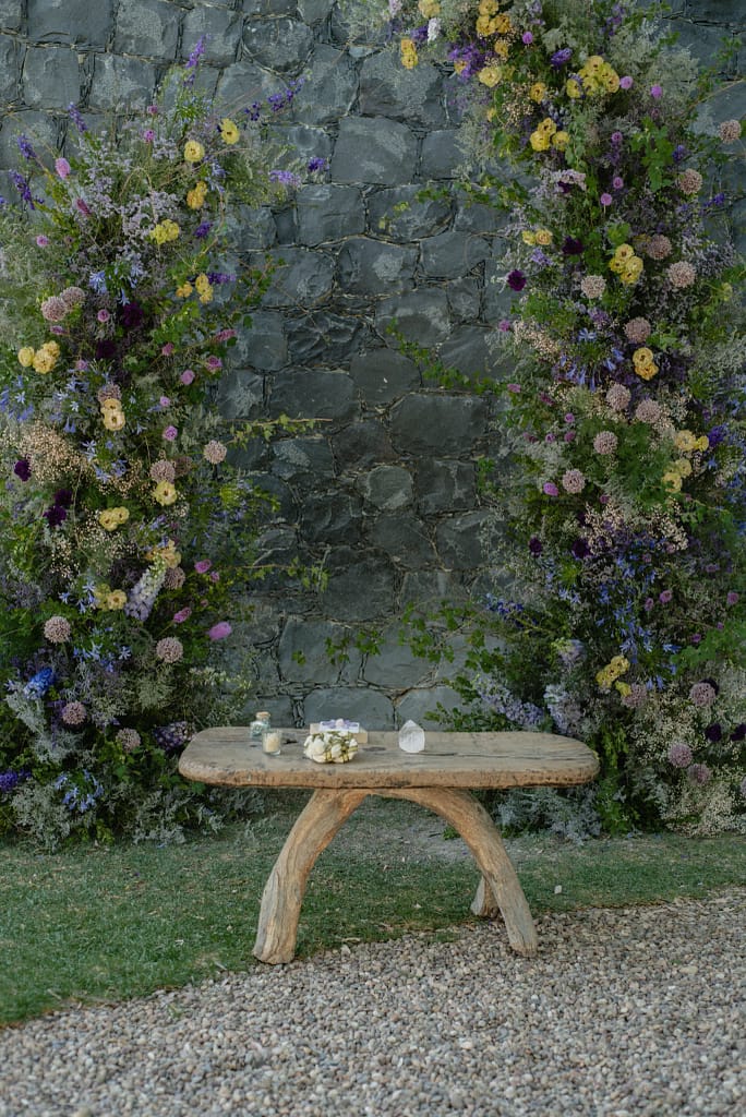 Romantic garden-style wedding flowers featuring mauve, blush, plum, and buttery yellow blooms styled by a wedding florist in San Miguel de Allende, Mexico. The bouquet and floral centerpiece include lisianthus, ranunculus, and delicate filler flowers, perfect for an elegant destination wedding. Captured at Casa Adela with soft candlelight and seasonal fruits, the floral design blends old-world charm with modern romance.
