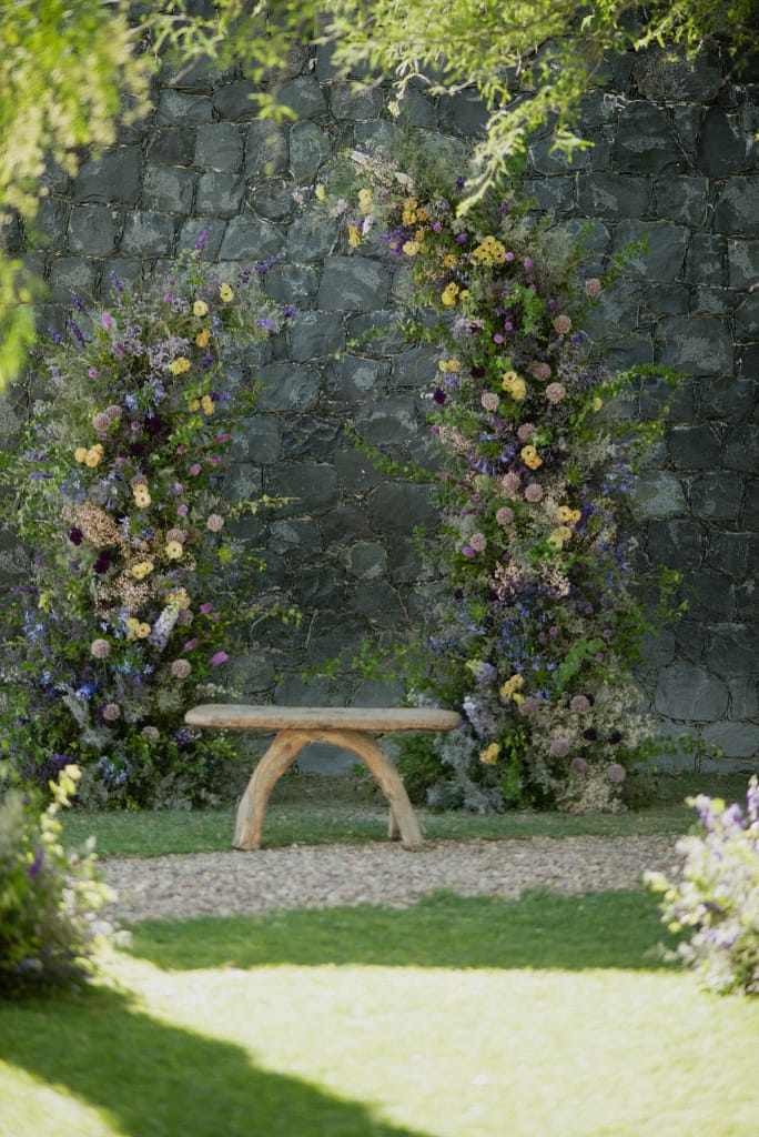 Romantic garden-style wedding flowers featuring mauve, blush, plum, and buttery yellow blooms styled by a wedding florist in San Miguel de Allende, Mexico. The bouquet and floral centerpiece include lisianthus, ranunculus, and delicate filler flowers, perfect for an elegant destination wedding. Captured at Casa Adela with soft candlelight and seasonal fruits, the floral design blends old-world charm with modern romance.