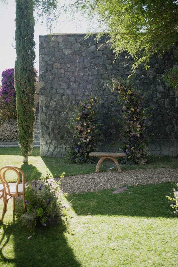 Romantic garden-style wedding flowers featuring mauve, blush, plum, and buttery yellow blooms styled by a wedding florist in San Miguel de Allende, Mexico. The bouquet and floral centerpiece include lisianthus, ranunculus, and delicate filler flowers, perfect for an elegant destination wedding. Captured at Casa Adela with soft candlelight and seasonal fruits, the floral design blends old-world charm with modern romance.